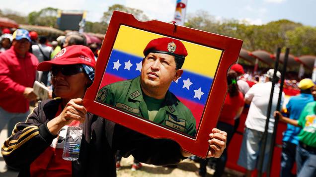 Mulher carrega um retrato de Hugo Chávez durante parada militar em homenagem ao aniversário de morte do ex-presidente venezuelano