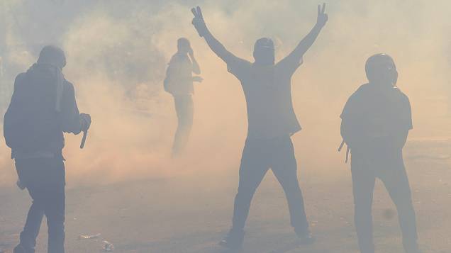 Estudantes venezuelanos caminham em meio a bombas de gás lacrimogêneo disparadas pela polícia durante um protesto contra o governo do presidente Nicolás Maduro, em Caracas - (12/03/2014)