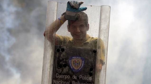 Estudante venezuelano usa escudo da polícia durante protesto contra o governo do presidente Nicolás Maduro, em Caracas - (12/03/2014)