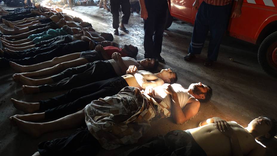 Parentes e ativistas inspecionando os corpos das pessoas que podem ter sofrido um  ataque por gás na região de Ghouta, nos arredores de Damasco