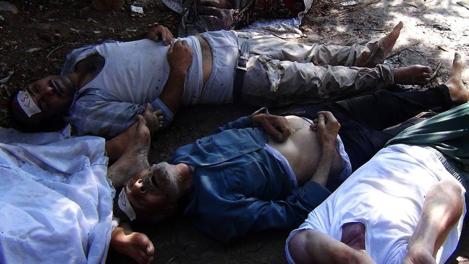 Parentes e ativistas inspecionando os corpos das pessoas que podem ter sofrido um  ataque por gás na região de Ghouta, nos arredores de Damasco