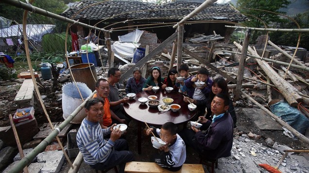 Moradores locais tem uma refeição em família fora de sua casa destruida pelo terremoto que atingiu o condado de Lushan, na província de Sichuan, China