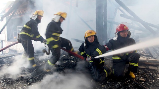 Bombeiros tentam apagar o incêndio que destruiu parte da aldeia tibetana no condado de Shangri-La, na China