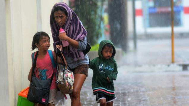 Mãe e seus filhos passam por uma rua durante chuva e ventos fortes, após tufão Haiyan atingir Cebu City, na região central das Filipinas
