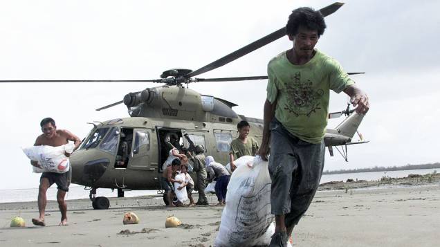 Sobreviventes do tufão Haiyan, da aldeia costeira de Capiz, transportam sacos contendo alimentos entregues pelas Forças Armadas, nas Filipinas