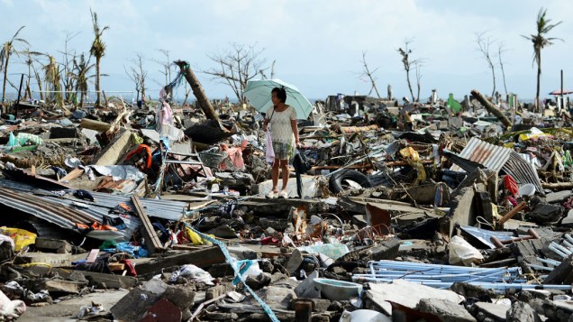 Mulher caminha nos escombros de casas destruídas pelo tufão Haiyan em Tacloban, nas Filipinas