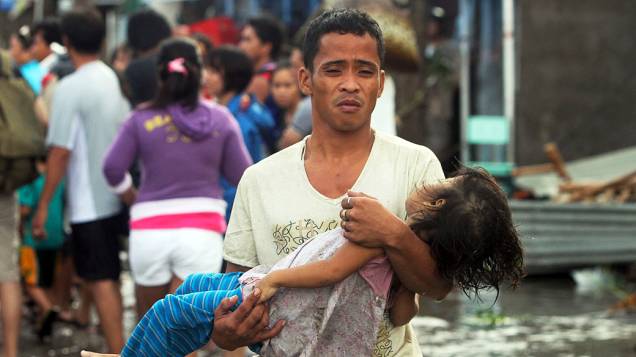 Pai leva o corpo de sua filha para o necrotério depois do tufão Haiyan atingir Tacloban, na província de Leyte, nas Filipinas