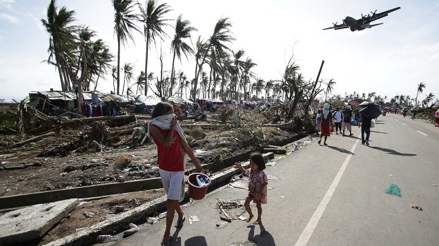 Moradores observam a chegada de um avião C-130 carregado de mantimentos em Tacloban (Filipinas)