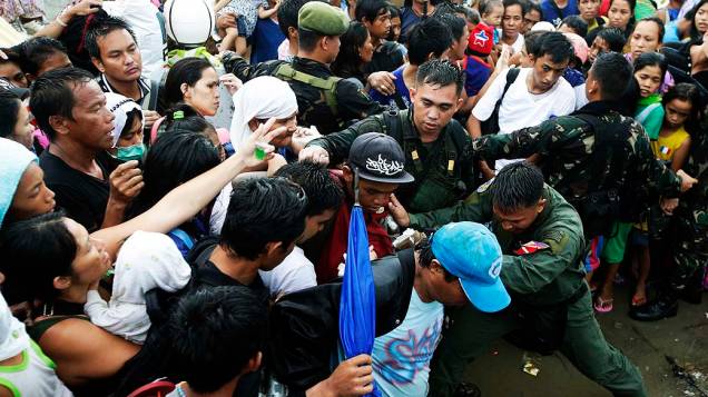 Soldados tentam conter pessoas desesperadas ao tentar embarcar no aeroporto de Tacloban