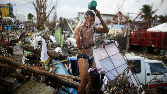 Homem toma banho em meio a escombros na cidade Tacloban, região central das Filipinas