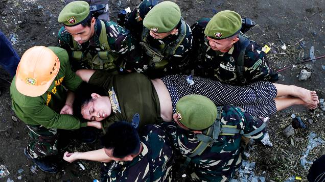 Soldados socorrem mulher que desmaiou ao tentar embarcar em avião em Tacloban, nas Filipinas