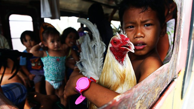 Menino dentro de um ônibus com sua família antes  de deixar a cidade de Tacloban, nas Filipinas
