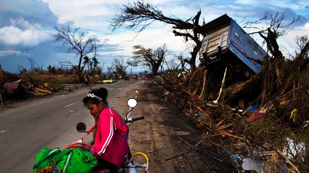 Sobrevivente do tufão Haiyan é fotografada entre ruínas de casas destruídas na cidade de Tacloban
