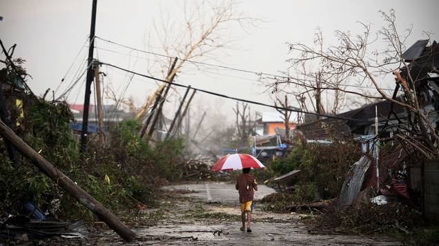 Mulher caminha por rua coberta por destroços causados pelo tufão Haiyan, nesta segunda-feira (18), em Jaro, nas Filipinas