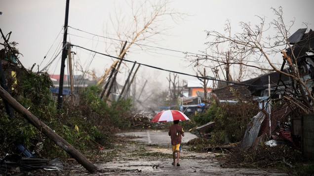 Mulher caminha por rua coberta por destroços causados pelo tufão Haiyan, nesta segunda-feira (18), em Jaro, nas Filipinas