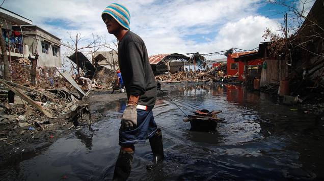 Homem retira lama e detritos em uma área devastada em Tacloban, Leyte, nas Filipinas