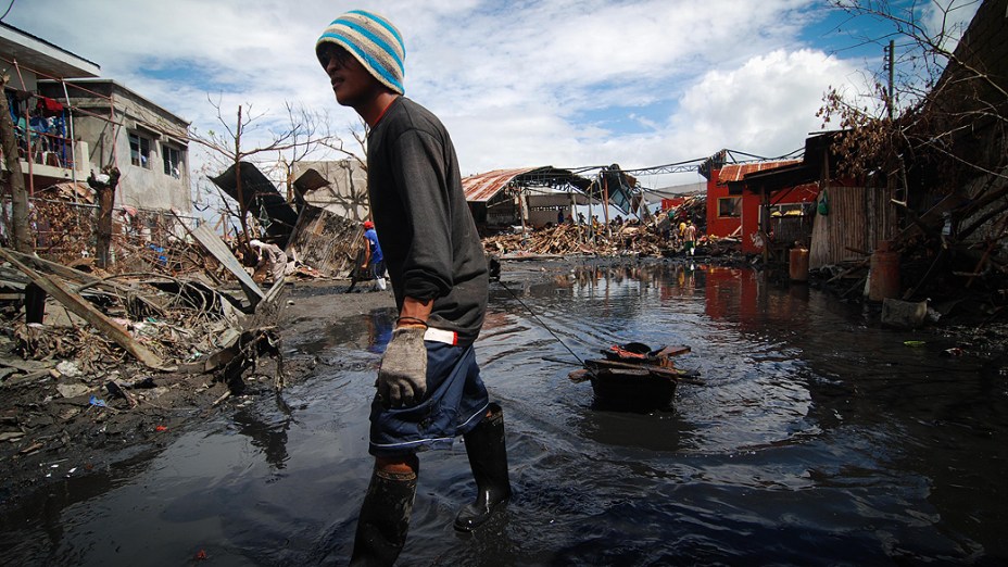 Homem retira lama e detritos em uma área devastada em Tacloban, Leyte, nas Filipinas