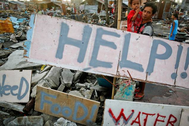 Sobreviventes escrevem mensagens pedindo ajuda para sua comunidade em uma área totalmente devastada pelo tufão Haiyan em Tacloban, nas Filipinas