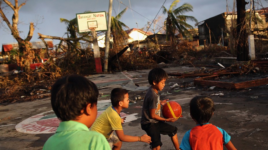 Crianças jogam basquete ao pôr do sol na cidade de Tacloban, nas Filipinas, destruída pela pessagem do supertufão Haiyan