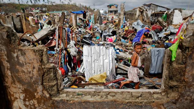 Menina caminha entre as casas destruídas pela passagem do supertufão Haiyan, à procura de pertences e itens que possam ser úteis, na cidade de Tacloban, nas Filipinas