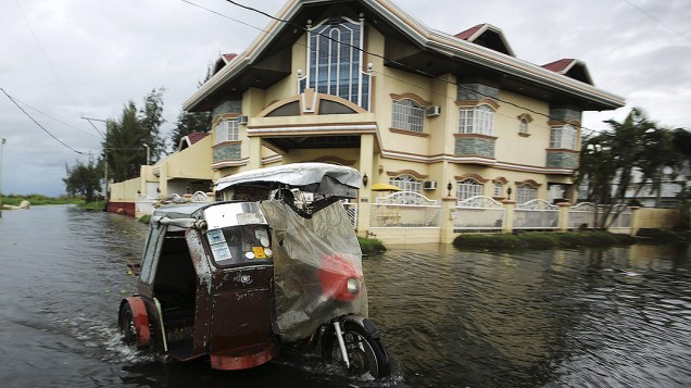 Homem transita com sua moto pelas ruas alagadas de Taguig, nas Filipinas após a passagem do supertufão Haiyan