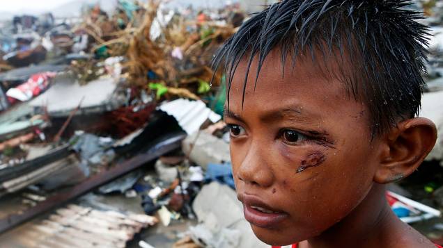 Um menino ferido durante a passagem do supertufão na cidade de Tacloban permanece nas ruínas da casa onde morava com a família