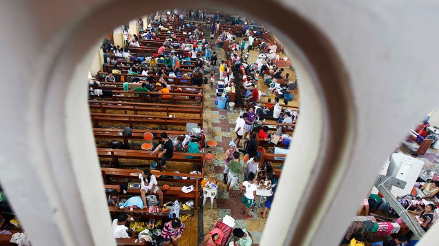 Sobreviventes procuram refúgio dentro de uma igreja católica que foi convertida em um centro de evacuação após a passagem do supertufão Haiyan na cidade Tacloban, Filipinas