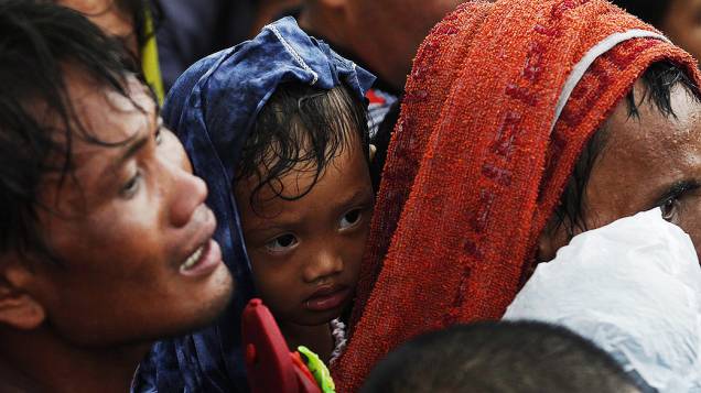 Homem tenta embarcar com seu filho em avião militar no aeroporto de Tacloban, a cidade foi devastada pela passagem do supertufão Haiyan, nas Filipinas