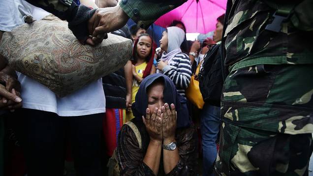 Mulher chora ao tentar embarcar em um avião de resgate no aeroporto da cidade de Tacloban