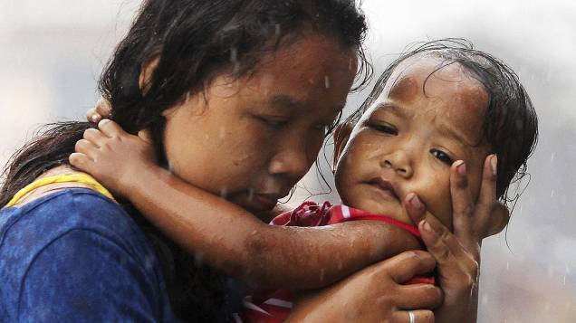 Mulher segura uma criança em Tacloban, na ilha de Leyte, Filipinas. Milhares de sobreviventes sofrem com a escassez de alimentos e água após a passagem do supertufão "Haiyan" na última sexta-feira (07/11)