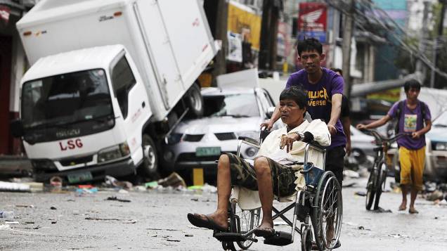 Pedestres caminham pelas ruas de Tacloban, na ilha de Leyte, Filipinas. Milhares de sobreviventes sofrem escassez de alimentos e água após a passagem do supertufão "Haiyan" na última sexta-feira (07/11)