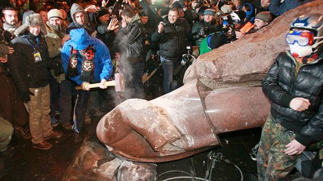 Homem destrói a marteladas uma estátua do fundador do Estado soviético Vladimir Lenin, derrubada por manifestantes pró União Europeia, em Kiev