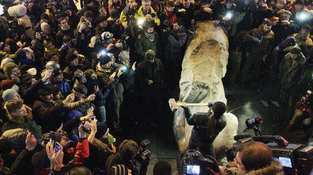 Homem destrói a marretadas uma estátua do fundador do Estado soviético Vladimir Lênin, derrubada por manifestantes pró União Europeia, em Kiev durante um protesto chamado A Marcha do Milhão