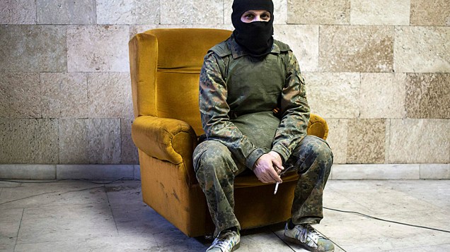 Militante pró-Rússia mascarado posa para uma foto dentro de um prédio do governo regional em Donetsk, leste da Ucrânia