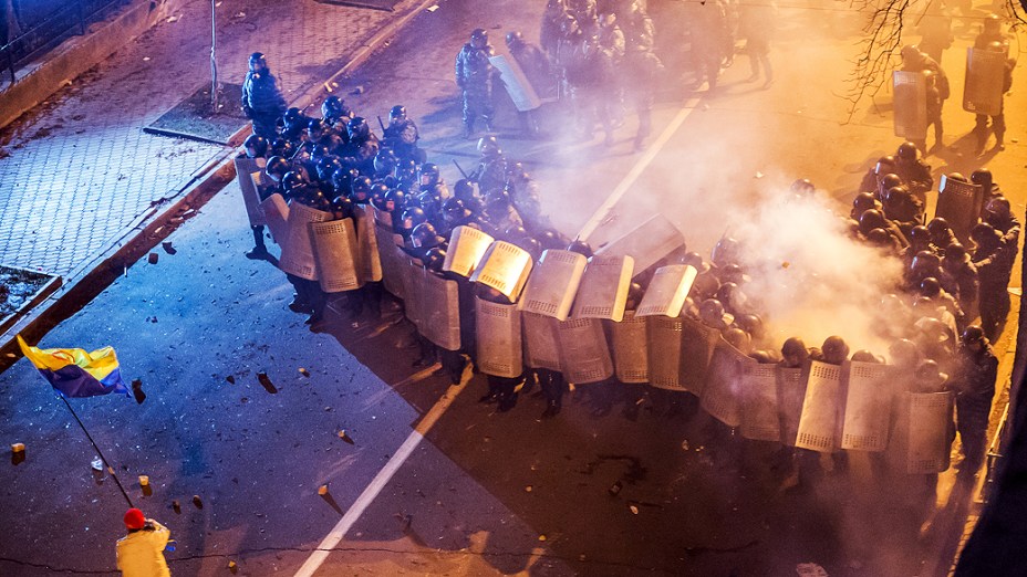 Manifestante segura a bandeira da Ucrânia em frente a um grupo de policiais durante protesto contra a decisão do presidente, Viktor Yanukovych, de suspender um acordo comercial com a União Europeia em frente à sede do governo, em Kiev