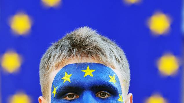 Manifestante pinta o rosto com a bandeira da União Europeia durante protesto na cidade ucraniana de Lviv