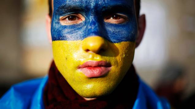 Manifestante com o rosto pintado com as cores da bandeira ucraniana posa para um retrato na Praça da Independência, em Kiev