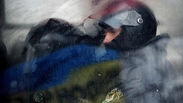 Policial observa de dentro de um ônibus, um bloqueio realizado por manifestantes durante protesto em Kiev