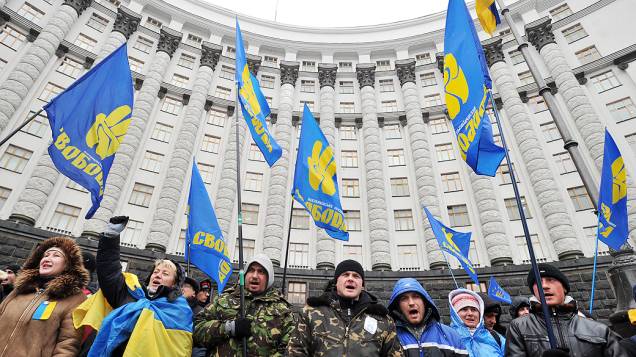 Manifestantes pró-União Europeia, seguram bandeiras do partido de oposição Svoboda, cantam mensagens de protesto e bloqueiam a entrada para o prédio do governo em Kiev