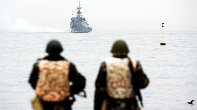 Integrantes da marinha ucraniana observam um navio russo posicionado na baía de Sebastopol, na região da Crimeia