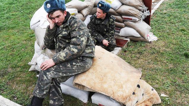 Pilotos da força aérea ucraniana sentados em sacos de areia na base aérea militar em Belbek, perto de Sebastopol, que está cercada por forças russas