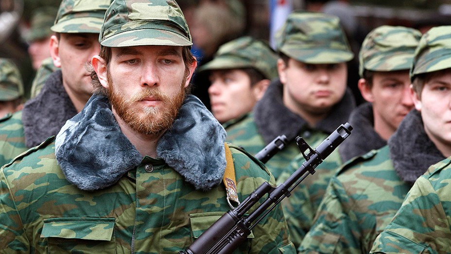 Homens armados, supostamente militares russos, marcham fora de uma base militar ucraniana na aldeia de Perevalnoye perto da cidade de Simferopol, na região da Crimeia