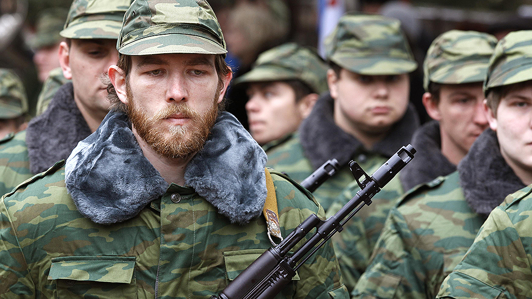Homens armados, supostamente militares russos, marcham fora de uma base militar ucraniana na aldeia de Perevalnoye perto da cidade de Simferopol, na região da Crimeia