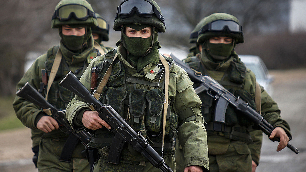 Homens armados, supostamente militares russos, marcham fora de uma base militar ucraniana na aldeia de Perevalnoye perto da cidade de Simferopol, na região da Crimeia