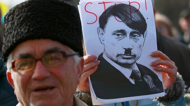 Manifestante pró-Ucrânia segura um retrato do presidente russo Vladimir Putin com referência a Adolf Hitler, durante um comício na cidade Simferopol na região da Crimeia