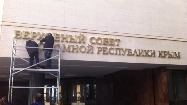Homens tiram o letreiro que dá nome ao Parlamento da Crimeia
