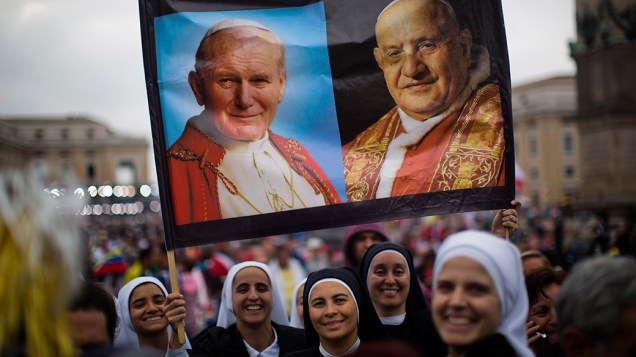 Freiras seguram cartazes com as fotografias de João Paulo II e João XXIII que foram proclamados santos pela Igreja Católica