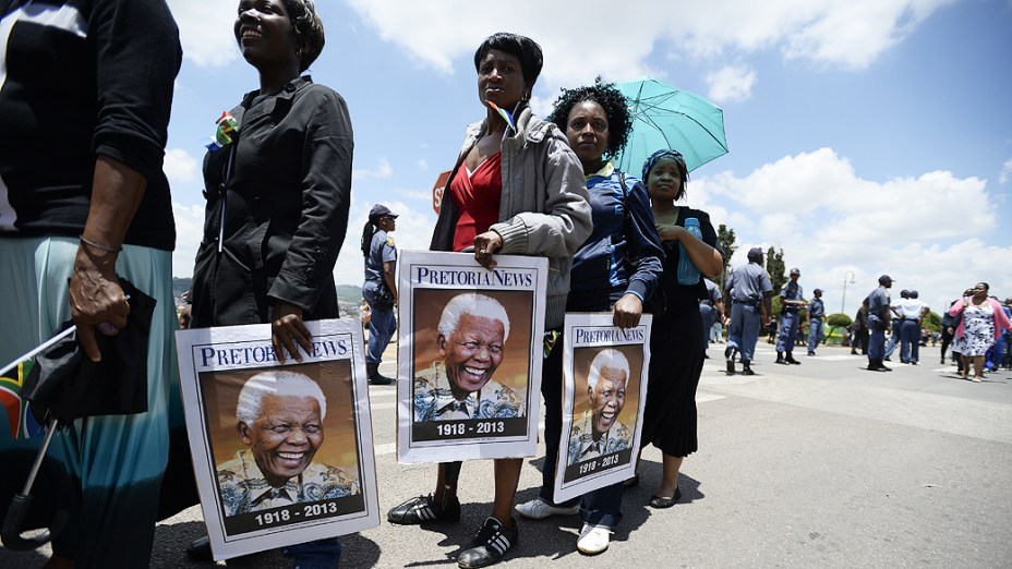 Sul-africanos seguram cartazes do ex-presidente sul-africano Nelson Mandela, em uma fila para ver seu corpo, em Pretória, África do Sul