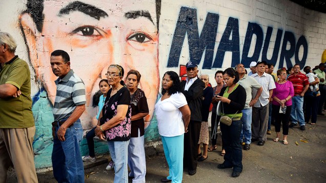 Pessoas fazem fila para votar em Petare, Caracas, diante da propaganda chavista