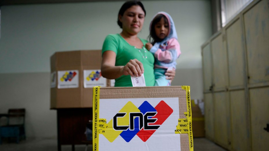 Mulher deposita seu voto em uma sessão eleitoral na favela Petare, em Caracas
